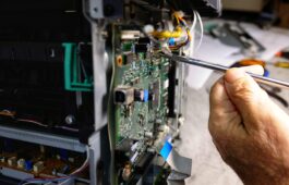 technician repairs photocopier with screwdriver