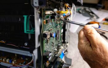 technician repairs photocopier with screwdriver