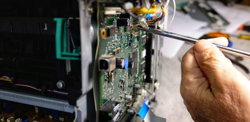 technician repairs photocopier with screwdriver